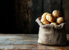 Burlap sack filled with fresh potatoes on a rustic wooden table, set against a dark wooden background, evoking a natural photo