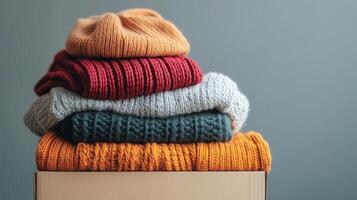 Warm knitted winter clothes and hats are folded into a cardboard box. The concept of relocation or humanitarian aid photo