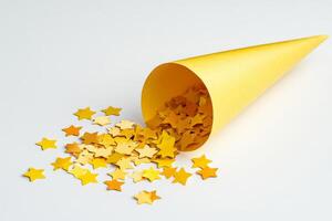 bright yellow cone on a white background is overflowing with colorful paper stars, creating a lively and celebratory scene photo