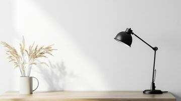 Sleek workspace featuring black lamp, pampas grass vase, natural light revealing shadows on pristine white wall photo