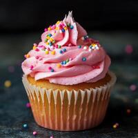 Delicious Cupcake Topped with Pink Frosting and Colorful Sprinkles on Dark Surface photo