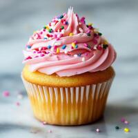 Delicious Cupcake With Pink Frosting and Colorful Sprinkles on Marble Surface photo