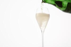 Sparkling wine pours from green bottleneck, creates bubbles. photo
