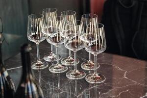 Few empty wine glasses on table near sparkling wine bottles. Wine tasting concept. photo