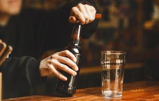 Bartender Opens Bottle of Beer on Polished Bar Counter at Vibrant Tavern During Evening Hours photo