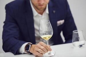 European wine enthusiast evaluating white wine at wine tasting based color rating, close up faceless shot. photo