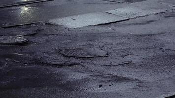 Wet asphalt with raindrops and puddles in the pits around the manhole in rainy weather. video
