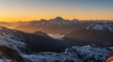 Snowy Mountain Peaks at Sunrise with Golden Light and Cloud Inversion photo