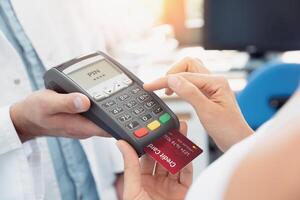 A person holding a credit card and a credit card reader photo