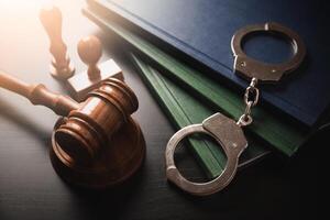 Handcuffs, gavel and books on a wooden table photo