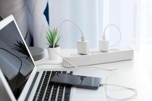 A laptop and charger are connected to a power strip photo