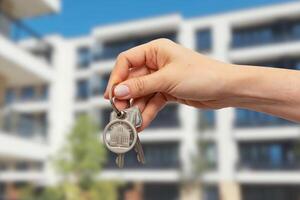 A person holding keys to a house in front of a building photo