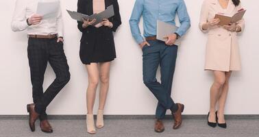Four business people standing in front of a white wall photo