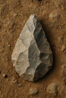 Flint hand axe on textured ground with natural earthy lighting. photo