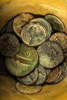 Ancient Roman coins collection in a container, close-up view. photo