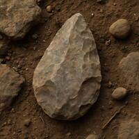 Stone hand axe on rough soil with rocks and natural textures. photo