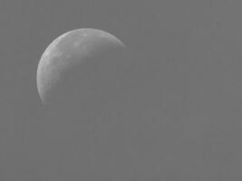 Half moon in detail with visible craters against a soft gray sky. photo