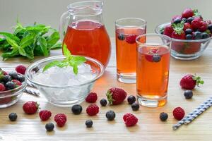 Enjoy a vibrant selection of berry infused drinks in tall glasses with ice, fresh mint, and mixed berries ideal for lively summer gatherings and celebrations. photo