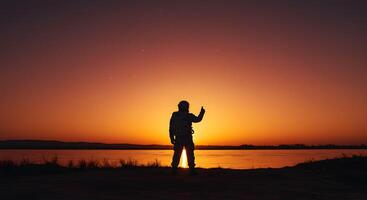 A silhouette of a man standing on a beach at sunset photo