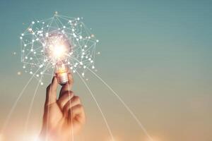 New ideas and imagination Creativity and inspiration Technological innovation. Hand holding brain digital network and abstract science light bulb inside on networking connection on sky background. photo