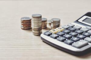 Money and coins stack, calculator and some stationery on wood table, Front view with copy space. Accounting and financial economic calculation concepts photo
