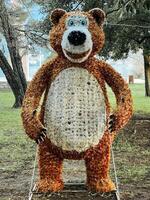 Fluffy figure of a smiling bear stands near the trees in a clearing photo