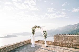 Rectangular wedding arch stands on an observation deck in the mountains above the sea photo