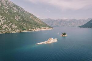 Islands of Gospa od Skrpjela and St. George in the Bay of Kotor against the backdrop of a mountain range. Montenegro. Drone photo