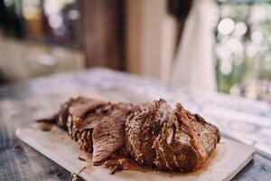 Pieces of roast beef lie in a row on a cutting board on the kitchen table photo