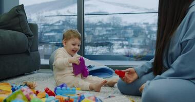 A happy baby plays on the floor with toys, with a loving woman video