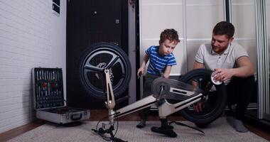 A man and boy bond fixing a bicycle, sharing laughter and joy video