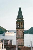 View from behind the bell tower of the Church of St. Nicholas of a cruise ship sailing on the sea. Perast, Montenegro photo