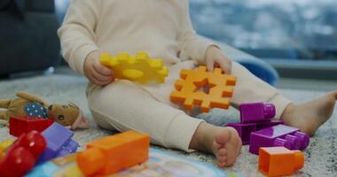A small baby is sitting happily on the floor playing with various toys video