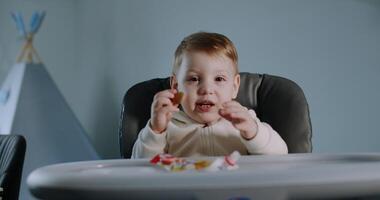 A baby and a boy enjoy treats in high chairs, sharing joy and laughter video