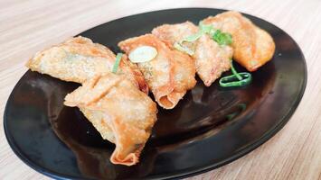 Deep fried gyoza crispy and golden colour set on black plate with studio lighting. photo