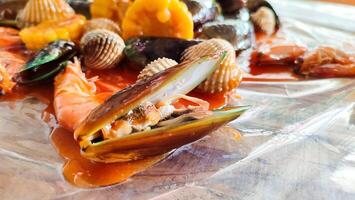cockles, shrimps, green mussels, corn, squid and crabs. Close up footage of various seafood with spicy sauce, photo