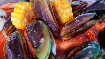 cockles, shrimps, green mussels, corn, squid and crabs. Close up footage of various seafood with spicy sauce. photo