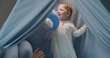A baby joyfully explores surroundings, playing with a blue balloon video