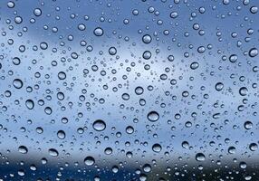 Rain Drops on Glass with Blurred Sky Background Close Up photo