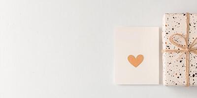 Gift box with speckled wrapping paper and heart card on white background photo