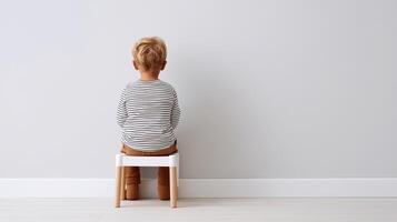 A toddler sits facing the wall in a time-out, symbolizing emotional protest, behavioral challenges, and stress in early childhood parenting and development. photo