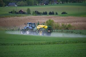 Tractor Spraying Field in Rural Landscape with Lush Green Vegetation photo