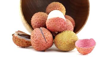 Fresh Lychee Fruits Pouring From a Wooden Bowl on a White Background photo