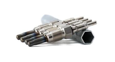 A set of four glow plugs next to a wrench, all against a clean, white background. photo