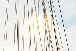 Rope cables against cloudy sky create industrial abstract pattern, background photo