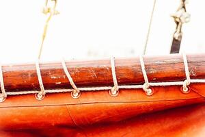 Sailboat mast and ropes with vibrant orange sail creating nautical background photo