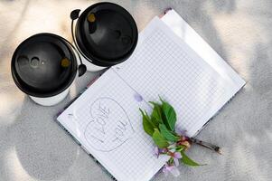 A notebook with a flower and two coffee cups photo