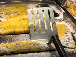 Powdered sugar-covered crepes with spatula on griddle photo