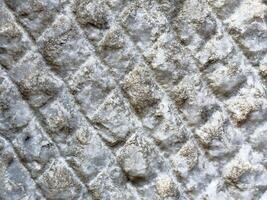 Close-up of rough textured pattern on stone surface with diamond shapes photo