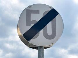 End of 50 km h speed limit sign against cloudy sky background photo
